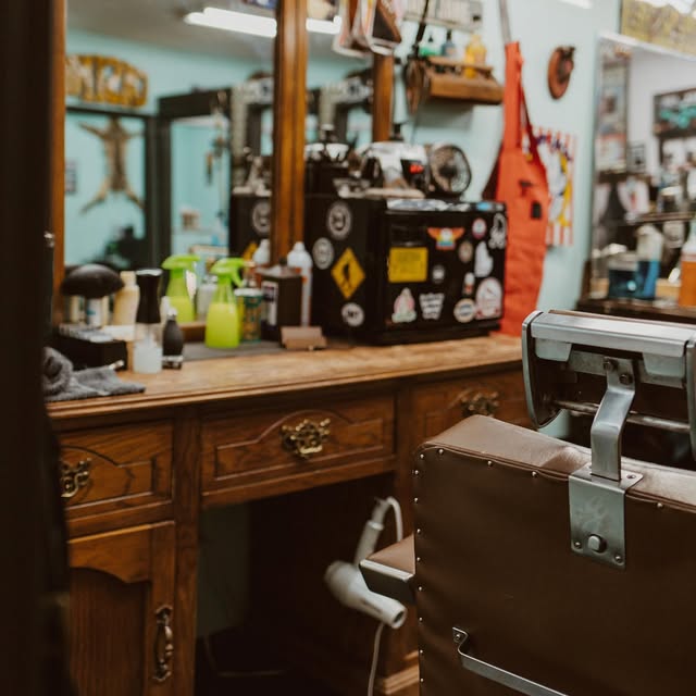 A wooden barber station stocked with sprays, clippers and a dryer